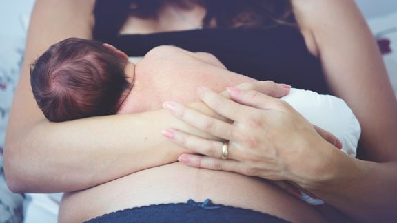 Woman breastfeeding with support from lactation consultant