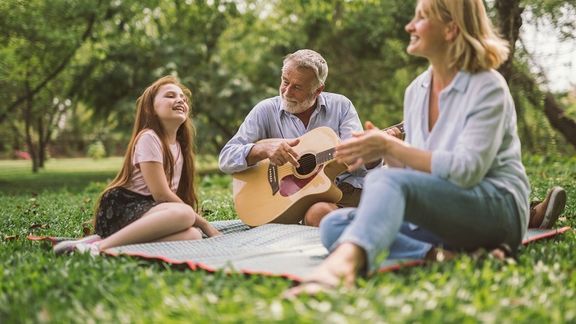 Family playing guitar outside with healthy ear, nose and throat