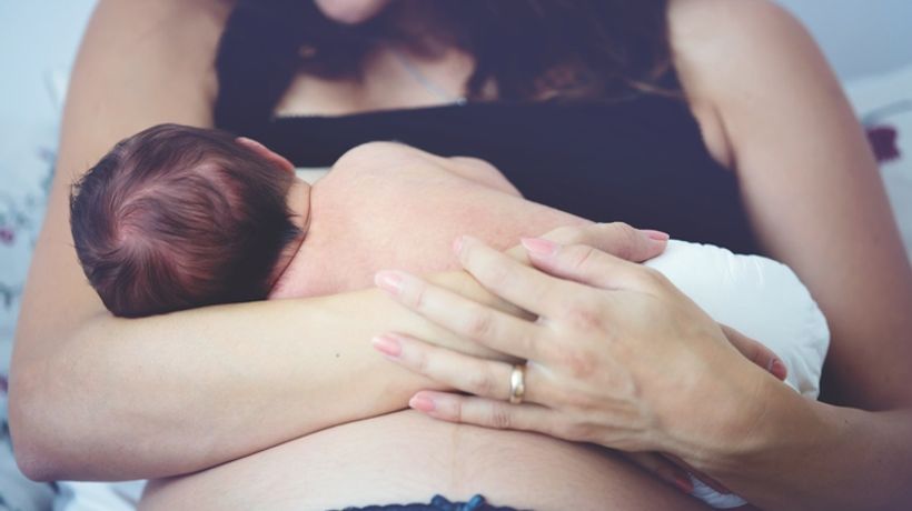 Woman breastfeeding with support from lactation consultant